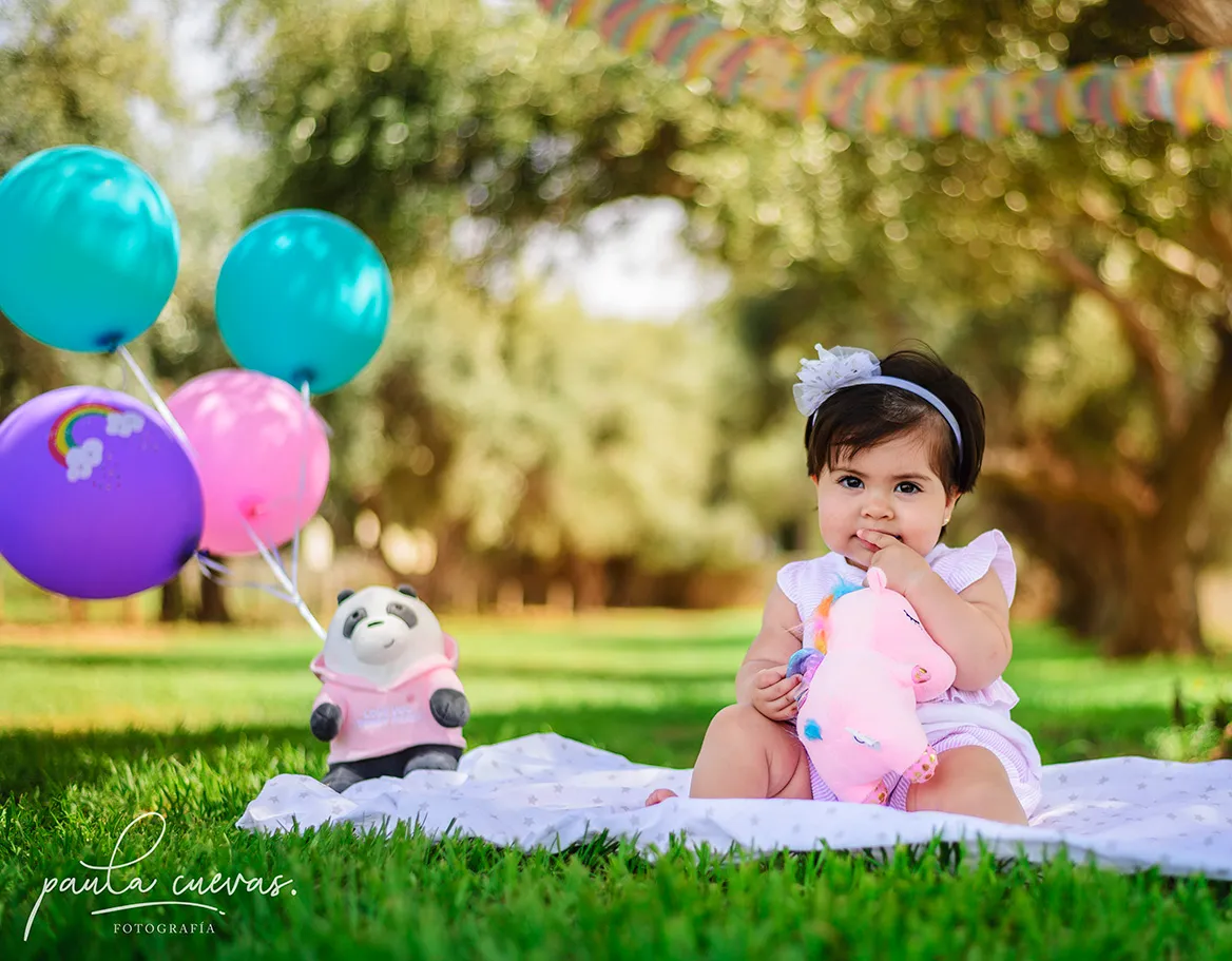 Retrato infantil de Alicia en exterior con globos y luz natural.