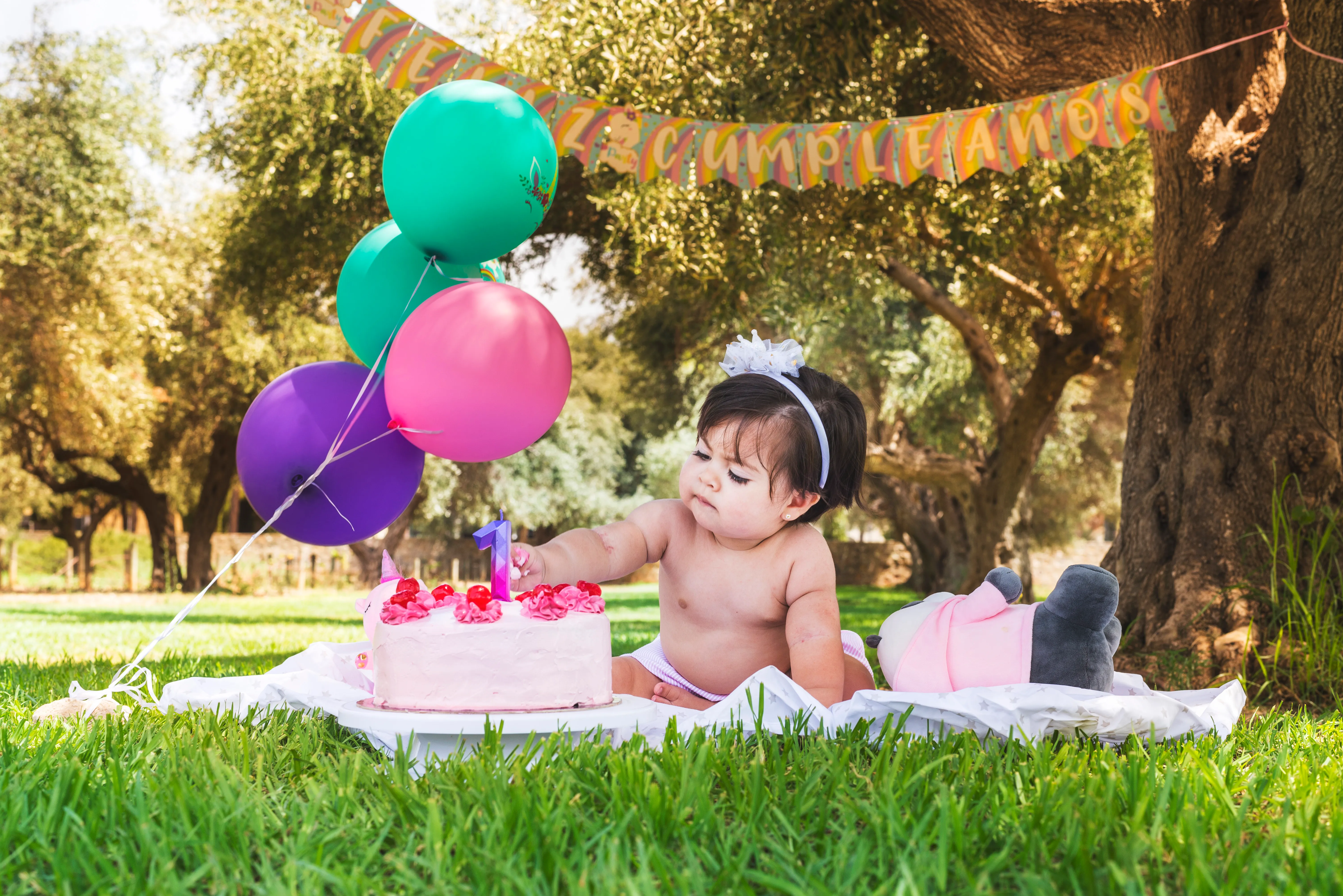 Retrato infantil de cumpleaños en exterior con globos, luz natural y encuadre amplio.